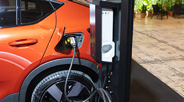 Un véhicule électrique aux couleurs vives branché sur une borne de recharge à l'intérieur